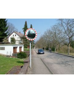 Verkehrsspiegel an einem Rohrpfosten am Straßenrand in Wohngebiet, installiert zur Verbesserung der Sicht an einer unübersichtlichen Einfahrt